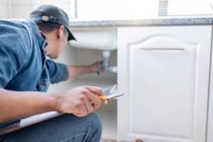 Licensed plumber performing a routine inspection on a home